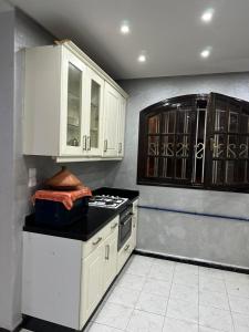 杰迪代Holikeys - El jadida - 2 Ch - Sidi Bouzid 001的厨房配有白色橱柜和炉灶。