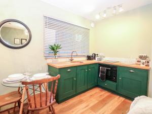 邦吉Goldcrest Hide的厨房配有绿色橱柜和带镜子的桌子