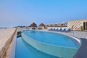 博尔本德尔The Fern Leo Beach Resort , Madhavpur的海滩旁的游泳池,配有蓝色椅子