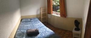 穆库热Hostel do Coreto的一间卧室配有一张带蓝色棉被的床和窗户。