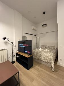 马德里Moratalaz Apartments的一间卧室配有一张床和一台平面电视