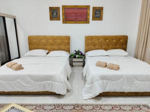 淡马鲁Homestay Temerloh Nasuha Homestay For Muslim Near Hospital with Private Pool Wi-Fi Netflix的卧室内的两张床,配有白色床单和枕头