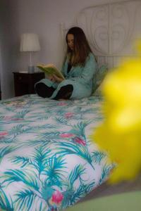 Fenais da LuzQuinta Physalis的坐在床上读书的女人