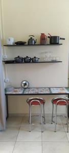 马里利亚Kitnet Marília的厨房配有2张凳子和1个带锅碗瓢盆的台面