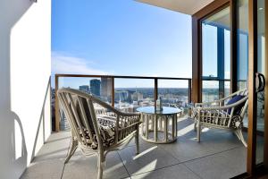 悉尼Chic Zenith Retreat -Vista, Skylight, Parking的大楼内的阳台配有两把椅子和一张桌子