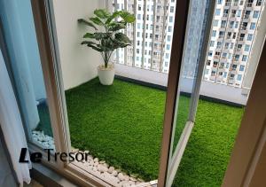 泗水Le Tresor Benson Apartment at Supermal Pakuwon的阳台拥有绿色的草地和植物