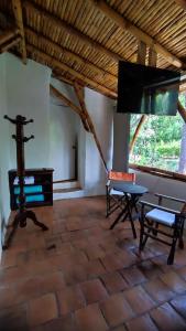 巴里查拉Cabañas Coloniales con Entorno Natural en Barichara的一间设有桌子、长凳和电视的房间