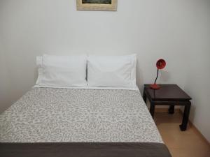 圣保罗Flat Manhattan Residence Service的一张带白色枕头的床和一张带台灯的桌子