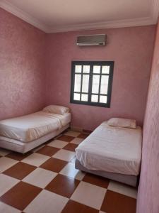 马拉喀什Villa Générosité的一张位于带 ⁇ 形地板的客房内的两张床