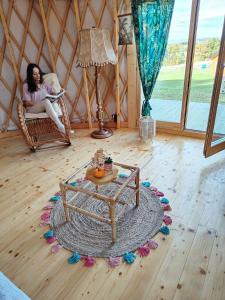 WolanyGlamping Niebiańska Osada Jurty Dolnośląskie & SPA的坐在圆顶帐篷里的女人,在房间里摆桌子