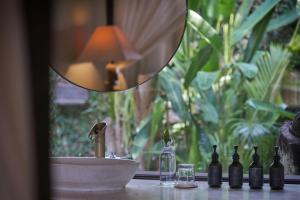 罗威那达迈酒店的一个带瓶子、水槽和镜子的柜台