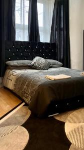 伦敦Comfy rooms. Shared East London Homestay.的一间卧室配有一张带黑色床头板的床
