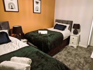 亨廷登6 Guests * 4 Bedroom * Free Wi-Fi *Huntingdon的一间卧室设有两张床和两个床头柜
