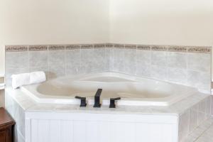 萨拉纳克莱克Sara Placid Inn & Suites的浴室设有白色浴缸,浴室设有瓷砖墙