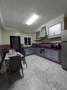 特莱姆森Appartement à louer à Tlemcen的一间带桌子的厨房和一间带紫色的厨房