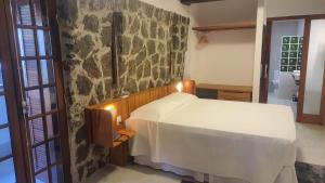 乌巴图巴科基耶酒店的卧室配有白色的床和石墙
