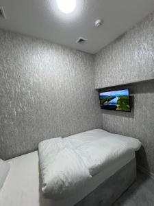 塔什干ReveL HoteL的卧室配有一张床铺,墙上配有电视