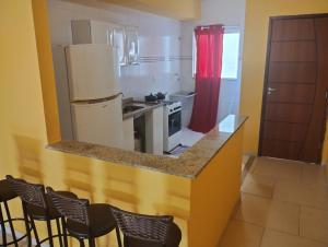 曼加拉蒂巴Apartamento Mangaratiba 2 suites的厨房配有带椅子的柜台和冰箱。