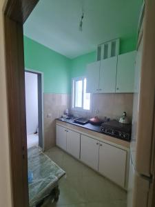 丹吉尔appart hotel tanger gzenaya的厨房设有绿色的墙壁和白色的橱柜。