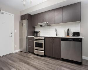 埃德蒙顿Hendrix Luxury Apartments by Corporate Stays的厨房配有木制橱柜和不锈钢用具