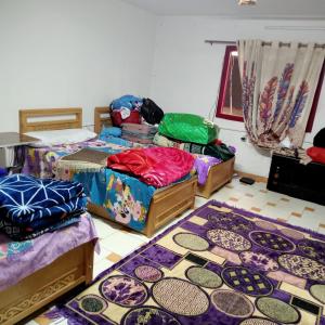 十月六日城بيت الطالبات的一间设有三张床的客房,地板上铺有地毯。