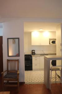皮纳马尔EDIFICIO CABO FRIO的厨房配有白色橱柜、椅子和桌子