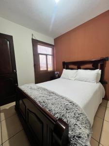 克萨尔特南戈Amplio Apartamento, en Colonia Cerezos, Tercer nivel的一间卧室配有一张带白色床单的床和一扇窗户。