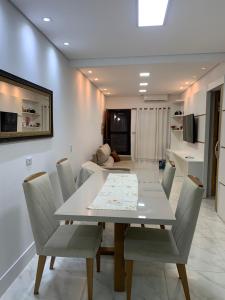 大普拉亚Casa com churrasqueira Guilhermina Praia Grande的一间配备有白色桌椅的用餐室