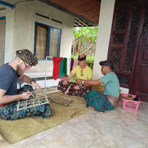 PetangPinge Traditional Village的坐在房子前面的地板上的三个男人