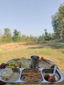 马哈巴莱斯赫瓦尔Yuva Yatri Campsite的桌上放有米饭和蔬菜的托盘