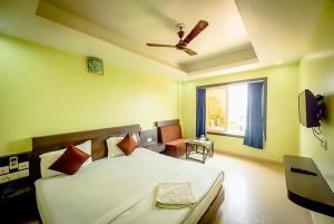 普里Goroomgo Deep Ganga Inn Near Sea Beach Puri的一间卧室配有一张带吊扇和窗户的床。