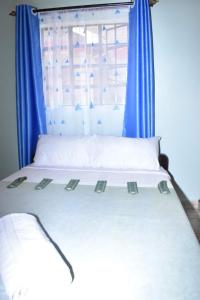 Ongata Rongai 3-bedroom, 2-bedroom, 1-bedroom serenity homes的白色的床,配有蓝色窗帘和窗户