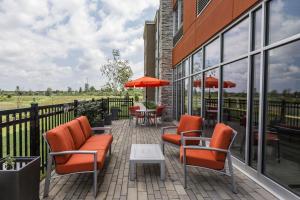 威兰Holiday Inn Express & Suites - Welland的庭院设有橙色椅子和桌子以及窗户。