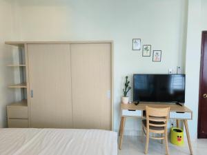 胡志明市Góc Hải Phòng Homestay Q4的一间卧室配有一张床和一张书桌及电视