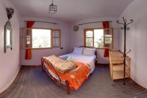 Aït BahaHotel De La Vallée的一间卧室配有一张带橙色棉被的床和两个窗户