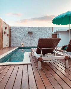 弗洛里亚诺波利斯Casa com piscina climatizada em frente à Praia do Santinho的游泳池旁的甲板配有椅子和遮阳伞