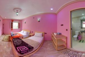 Aït BahaHotel De La Vallée的粉红色的卧室设有一张床和一间浴室。
