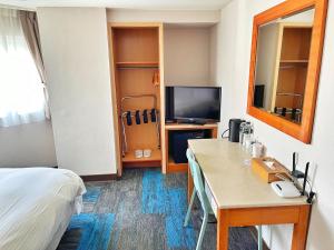 台北華麗大飯店Ferrary Hotel的客房设有床、书桌和电视。