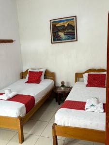 伊基托斯Hospedaje Casa Amazónica Iquitos的一间设有两张红色和白色床单的房间