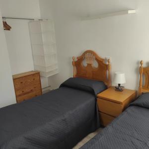 本迪亚Apartamento Altomira的一间卧室设有两张床和木制床头板