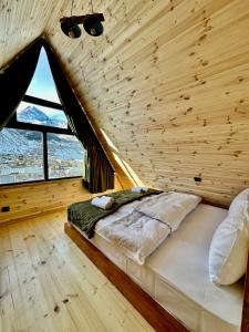 卡兹贝吉Hillside Kazbegi的木制客房的一张床铺,设有大窗户
