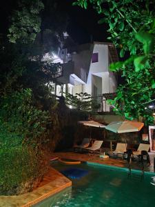 乌巴图巴Apartamentos Casa da Pedra的一座带椅子和遮阳伞的游泳池位于一座建筑旁边