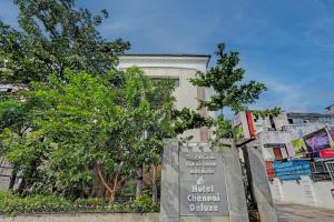 钦奈Palette - Chennai Deluxe Koyambedu的树木丛生的建筑前的标志