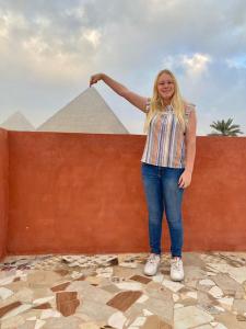 开罗Energy Of Pyramid Hotel的站在金字塔围墙旁的女人