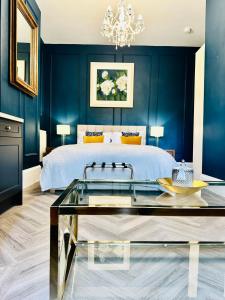 圣赫利尔泽西Eden Hotel - Beach Apartments & Suites的一间拥有蓝色墙壁的卧室和一张带玻璃桌的床