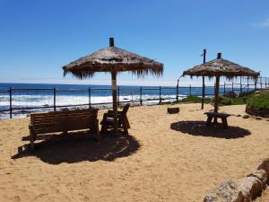 埃尔塔波Departamento AltoMar El Tabo Isla Negra的海滩上的两把长椅和遮阳伞