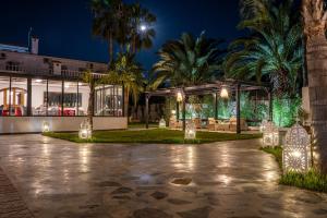 拉巴特Hôtel L'Hacienda的享有棕榈树和灯光的建筑的夜景