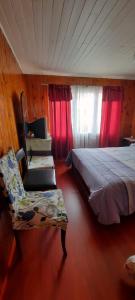 卡塔赫纳ALOJAMIENTO LAS LILAS的一间卧室配有一张床、一把椅子和红色窗帘