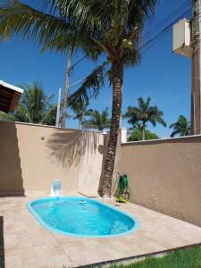 卡波布里奥Casa em Unamar, Cabo Frio - com piscina privativa的墙上的棕榈树游泳池