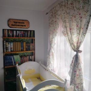 RaškaVujanac vikend kuća的一间卧室配有婴儿床和带窗帘的窗户。